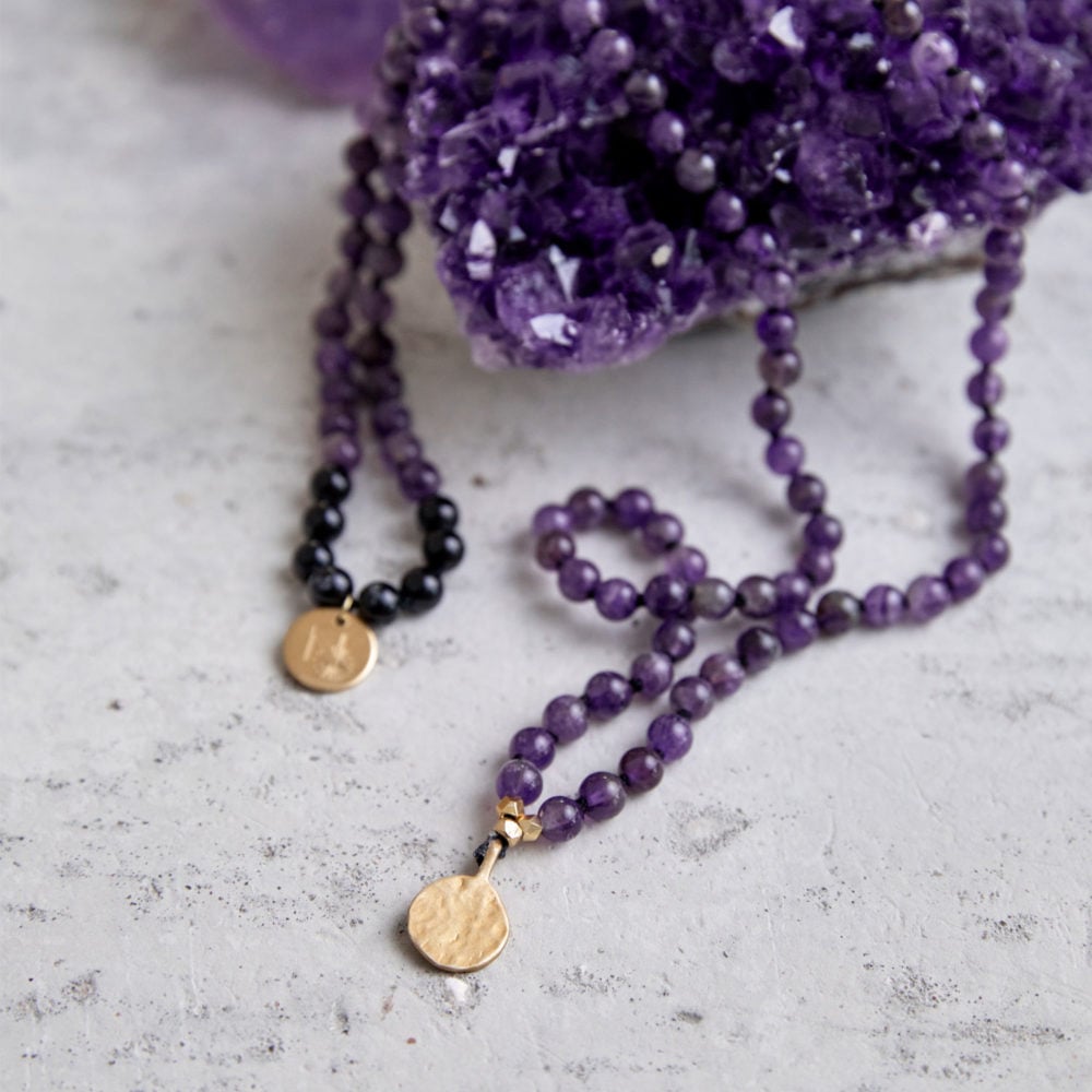 PEACE OF MIND Mala aus Amethyst und schwarzen Turmalin Steinen mit goldenen NAIONA Plättchen und Perlen und Amethyst Stufe.