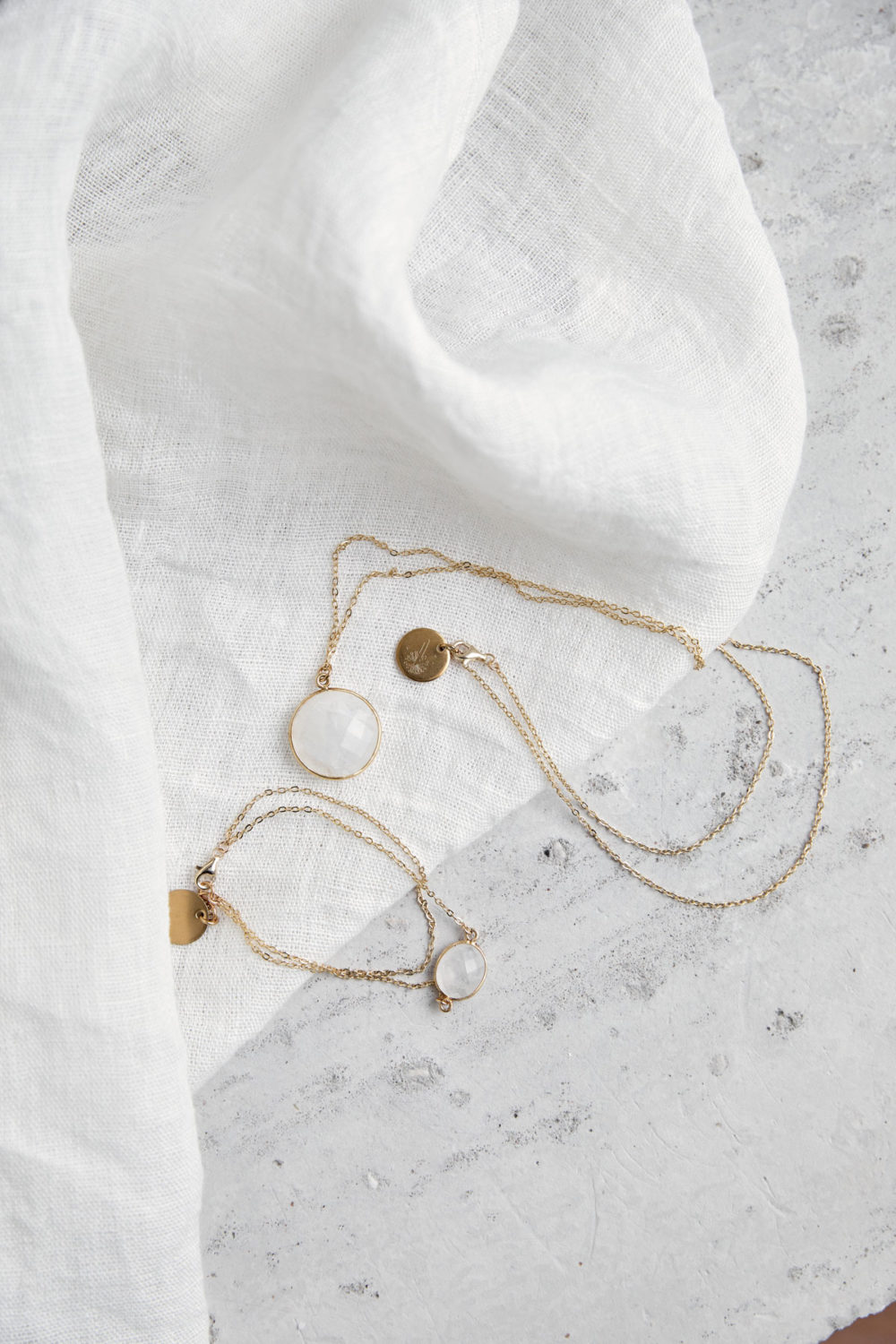 KAUPO Armband gold mit Mondstein weiß und goldenem NAIONA Plättchen und KAUPO Kette gold. Tuch.