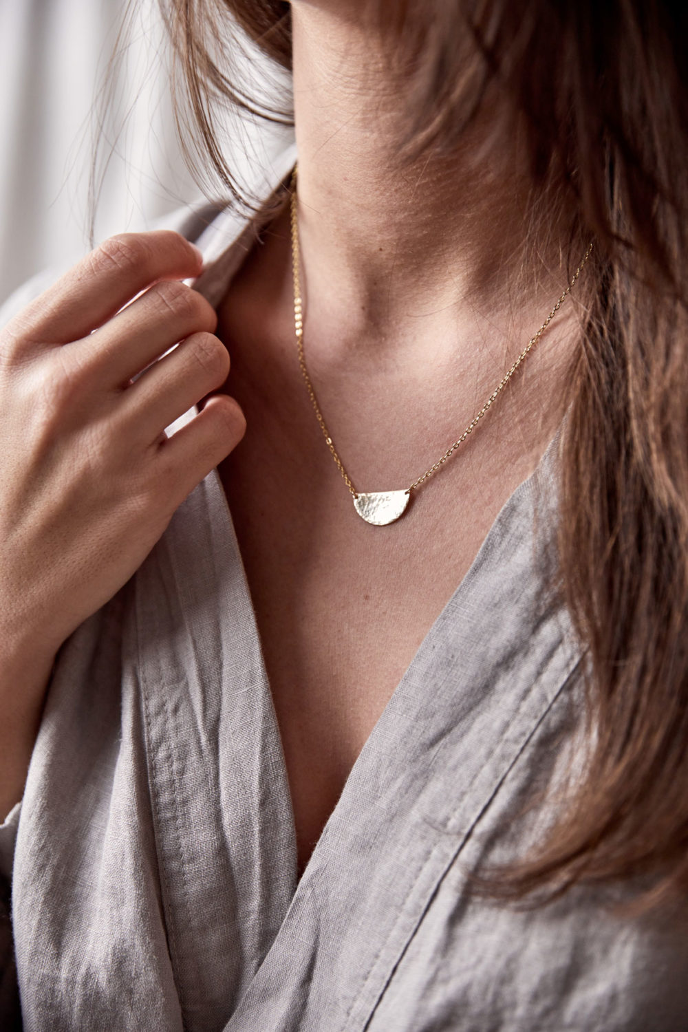 SIMPLICITY Kette gold mit goldenem Halbmond Plättchen und NAIONA Plättchen. Frau, Ausschnitt, Hemd.